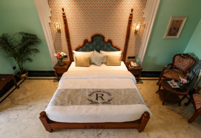 Teal wall with framed Rajasthani paintings + palm